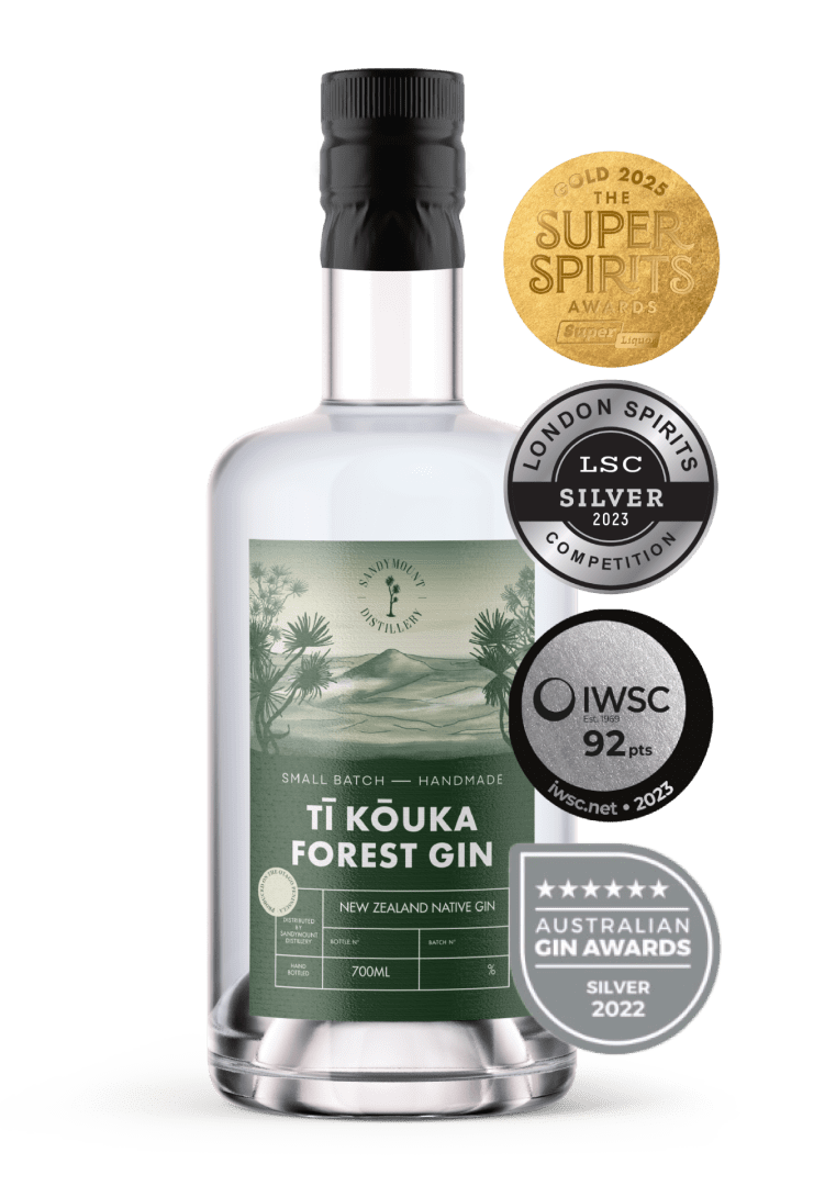 A clear glass bottle with clear liquid in it and a label on the front. The green label has illustrations of bush and a hill landscape, titled Tī Kōuka Forest Gin